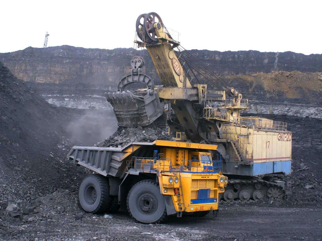 Excavator loading a yellow haul truck at an open-pit mine